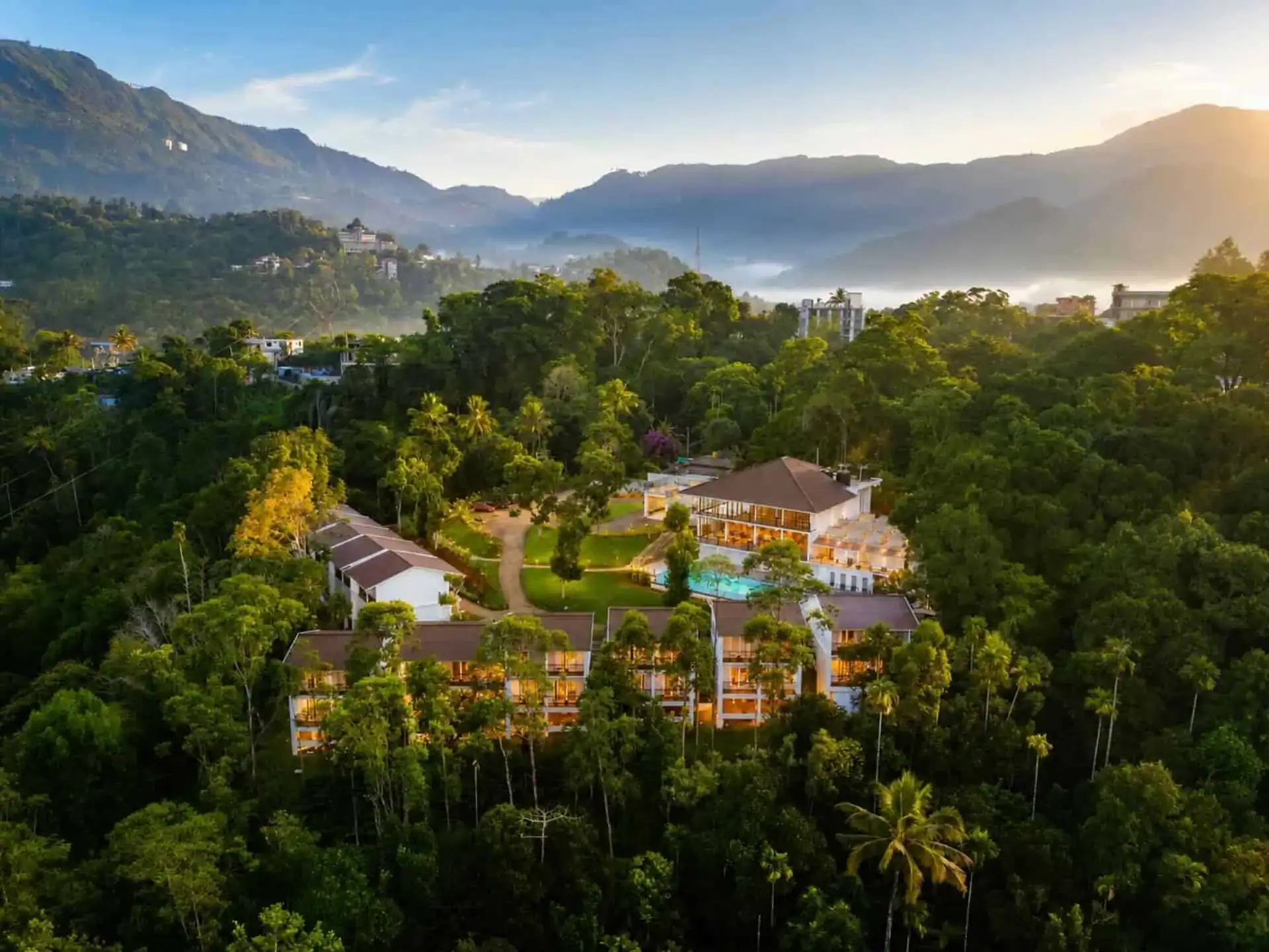 Drone aerial of resort in misty morning light with mountain ridges