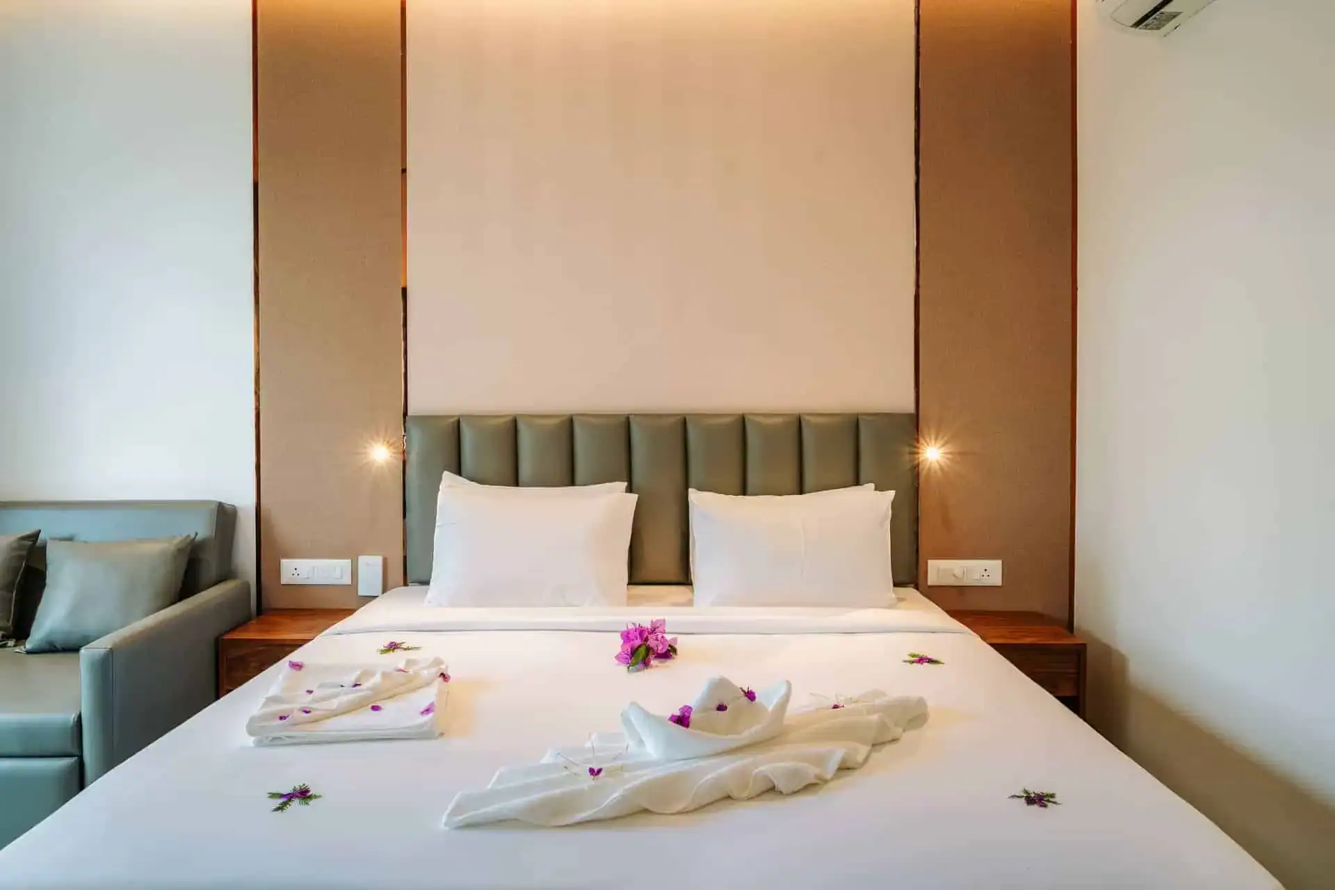 Bed detail with elaborate towel art and purple fresh flowers