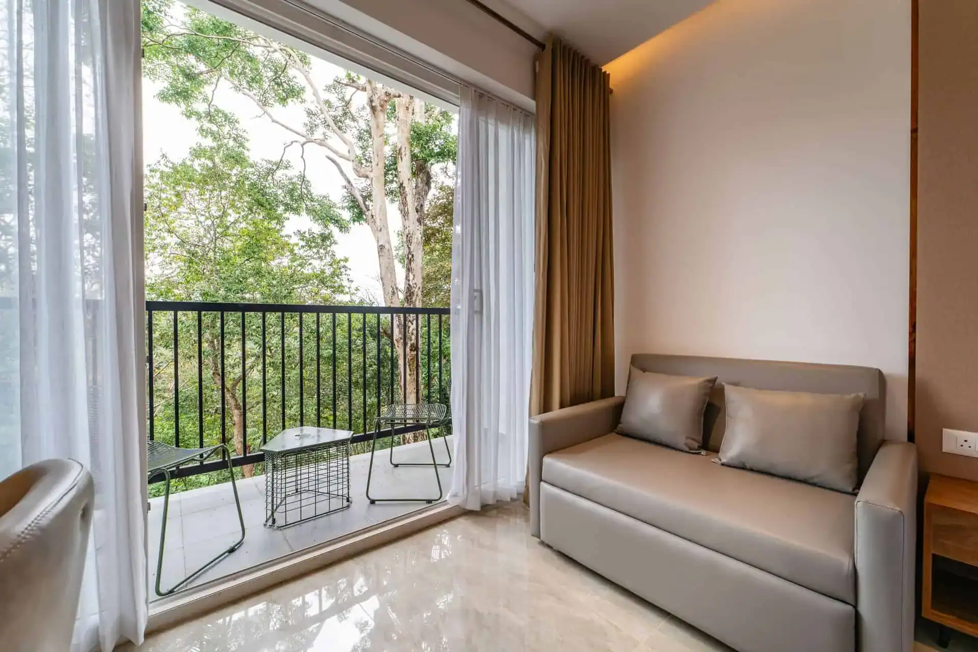 Grey sofa by sliding balcony door with eucalyptus canopy view
